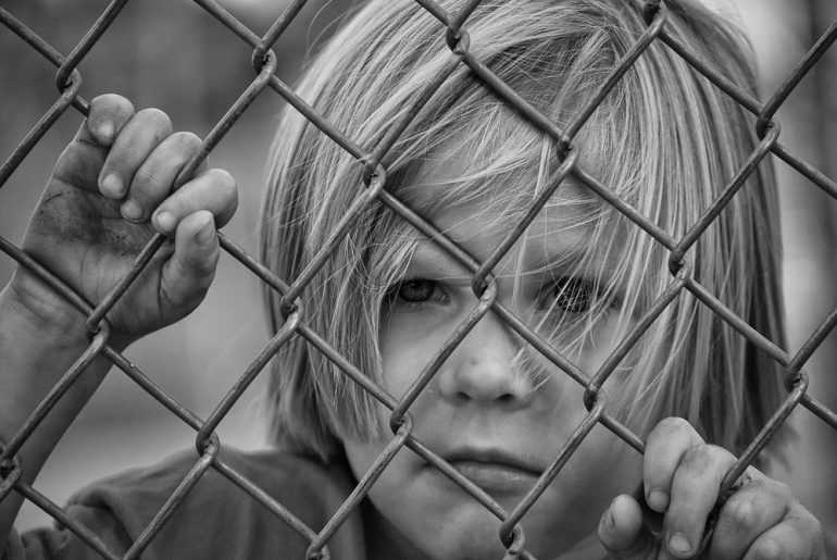 Kind hinter einem Zaun